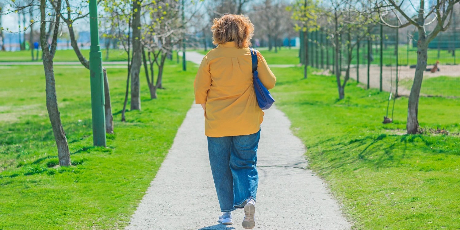 Eine Frau mittleren Alters in gelber Bluse und Jeans läuft eine Allee mit kahlen Bäumen entlang.. Artikel "Essen und Emotionen" öffnen.