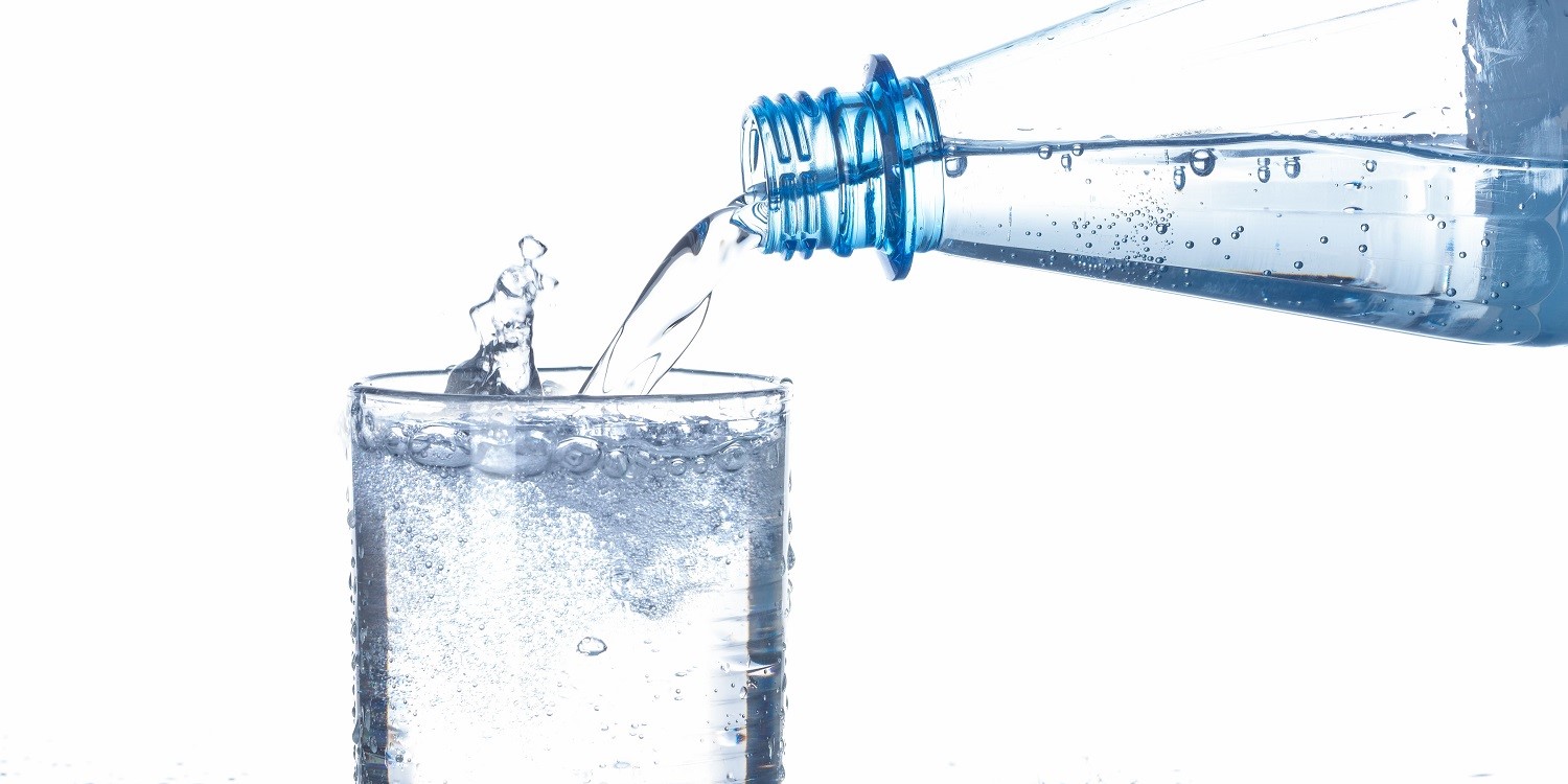 Aus einer Flasche wird Mineralwasser mit Kohlendioxid in ein Glas gegossen.. Artikel "Warum liebt unser Gehirn Bläschen?" öffnen.