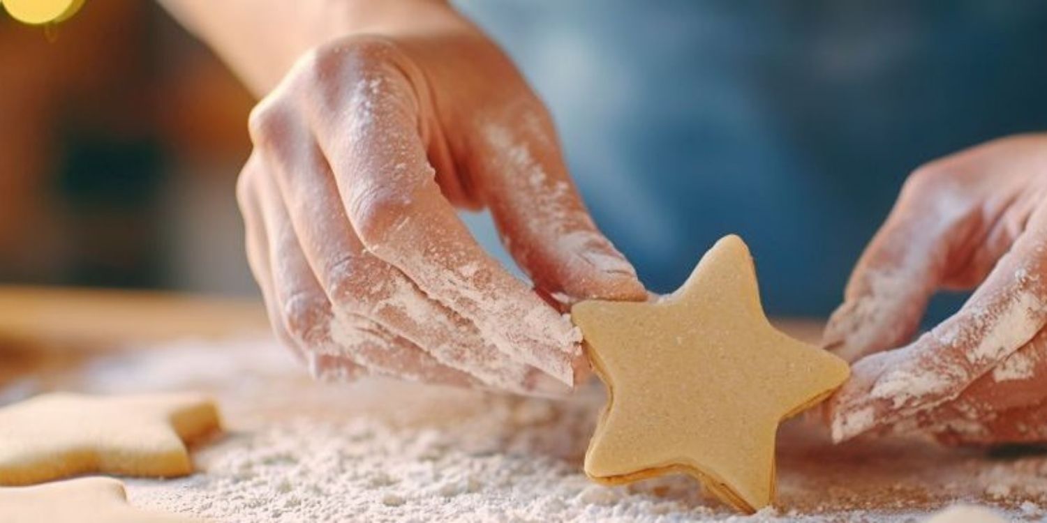 Bemehlte Frauenhände halte ein Plätzchen in Sternform in der Hand. . Artikel "Weihnachten in der Küche" öffnen.