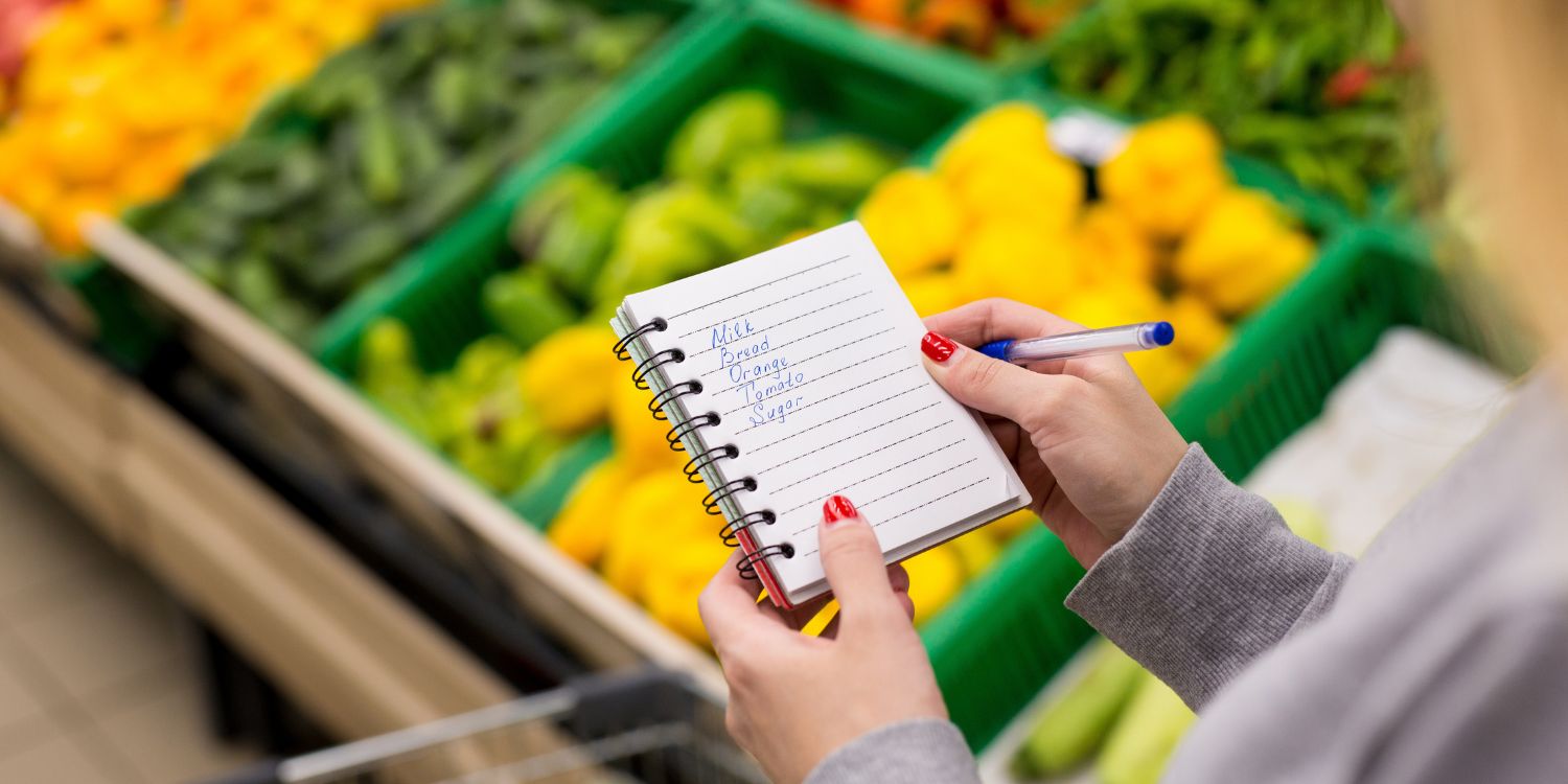 Eine Nahaufnahme von Frauenhänden mit einer Einkaufsliste in einem Notizbuch im Supermarkt.. Artikel "Aktionswoche „Zu gut für die Tonne!“ zum Mitmachen" öffnen.