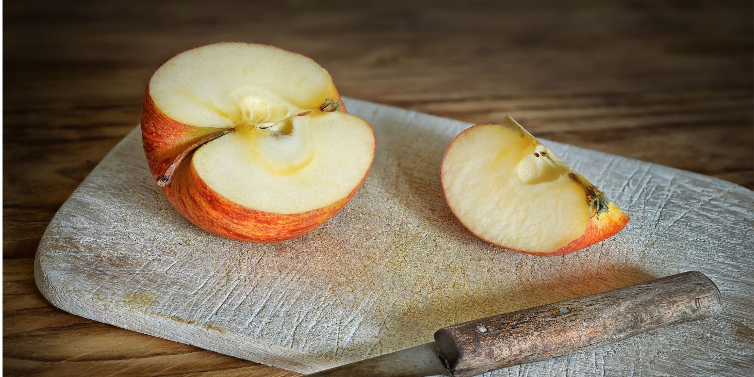 Auf einem Holzbrettchen liegen ein halber Apfel und ein Viertel, sowie ein Küchenmesser.. Artikel "Warum manche Äpfel brauner werden als andere" öffnen.