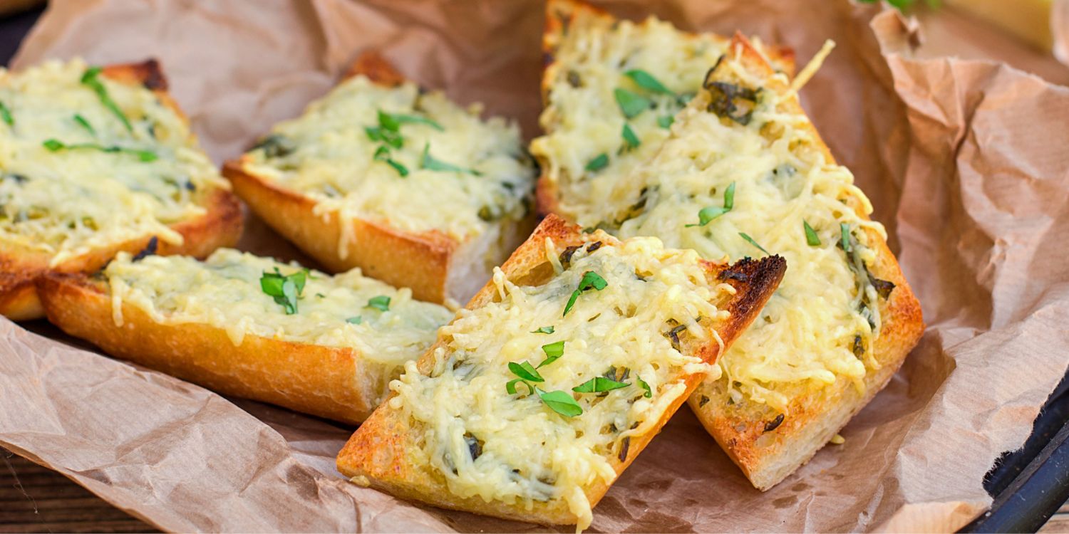 Auf Backpapier liegen Baguettestücke, mit Käse überbacken und mit Kräutern bestreut.. Artikel "So bleibt Brot im Sommer länger frisch" öffnen.