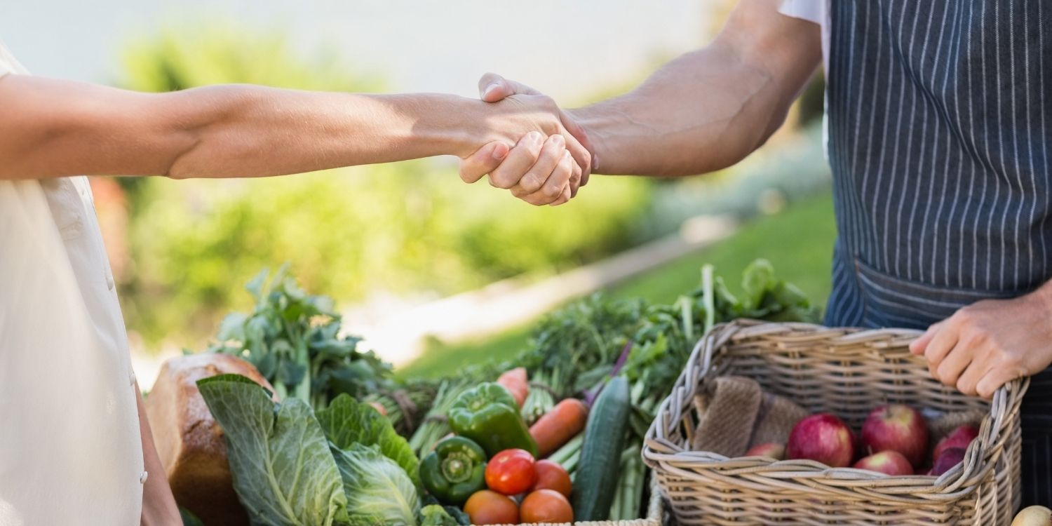 An einem Obst- und Gemüsestand reichen sich zwei Menschen die Hand. . Artikel "Deutscher Ernährungstag 2026" öffnen.