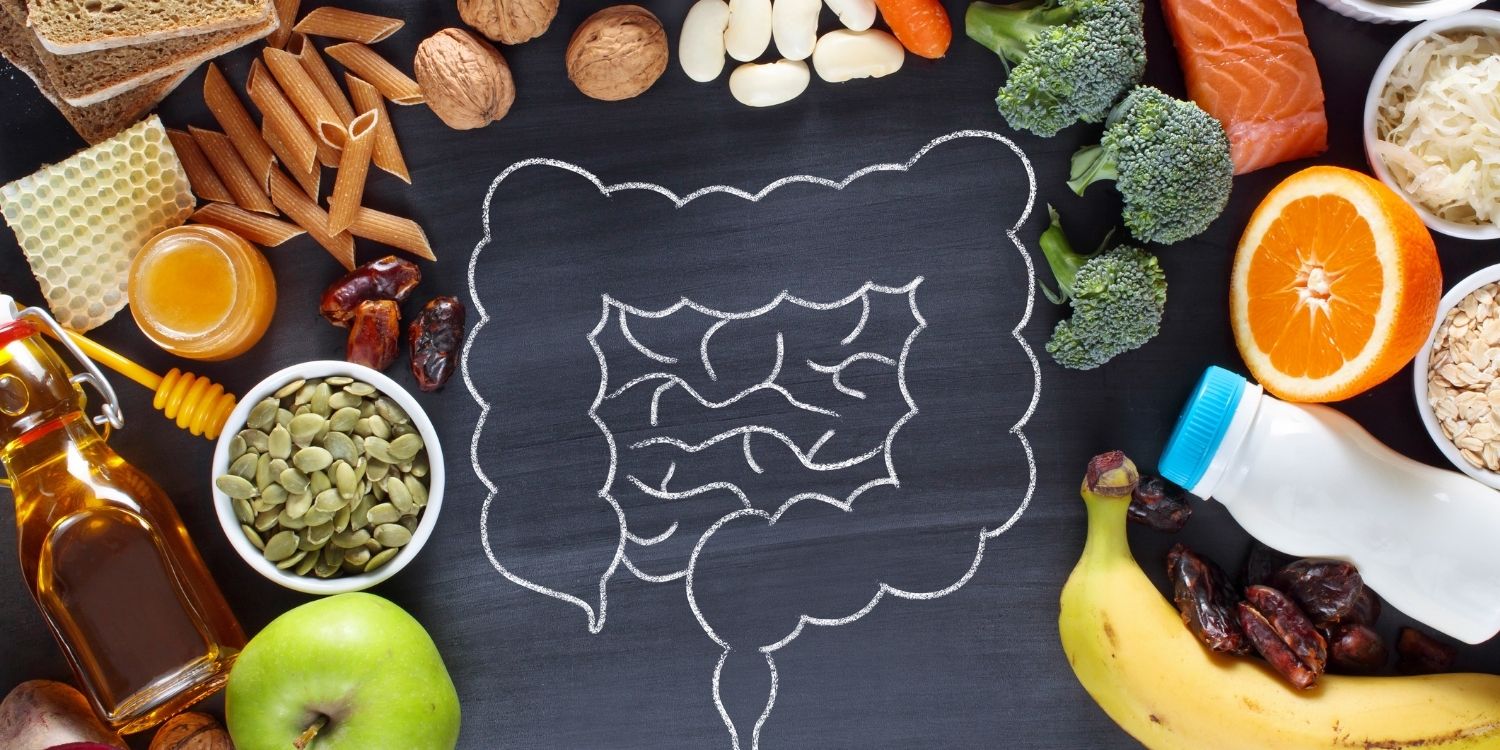 Auf einer schwarzen Tafel ist mittig ein Darm aufgezeichnet, ringsum liegen Lebensmittel wie Obst, Nüsse, Öl, Gemüse, Fisch und Vollkornprodukte.. Artikel "10 Billionen Mikroben im Visier der Wissenschaft" öffnen.