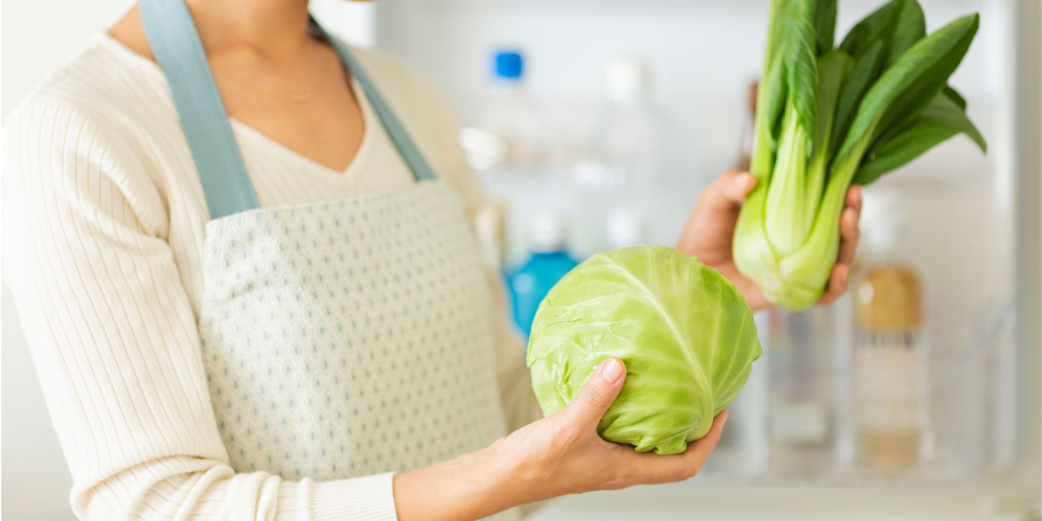 Eine Frau steht in der Küche und hält einen Fenchel und einen Weißkohl in den Händen. . Artikel "Ab in den Urlaub ohne Reste" öffnen.
