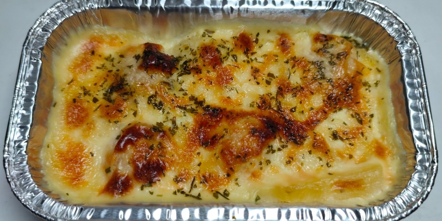 Ein mit Käse überbackenes Fertig-Pastagericht liegt in einer Aluschale. . Artikel "Mehr Fertiggerichte in Deutschland" öffnen.