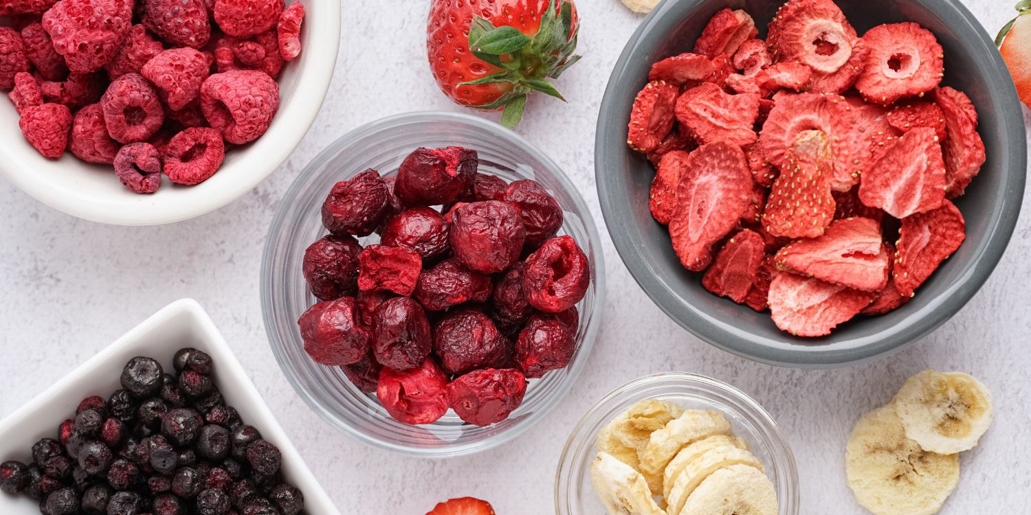Auf einem weißen Untergrund stehen mehrere Schüsseln mit gefriergetrockneten Himbeeren, Erdbeeren, Kirschen, Blaubeeren und Bananen.. Artikel "Gefriergetrocknete Früchte" öffnen.