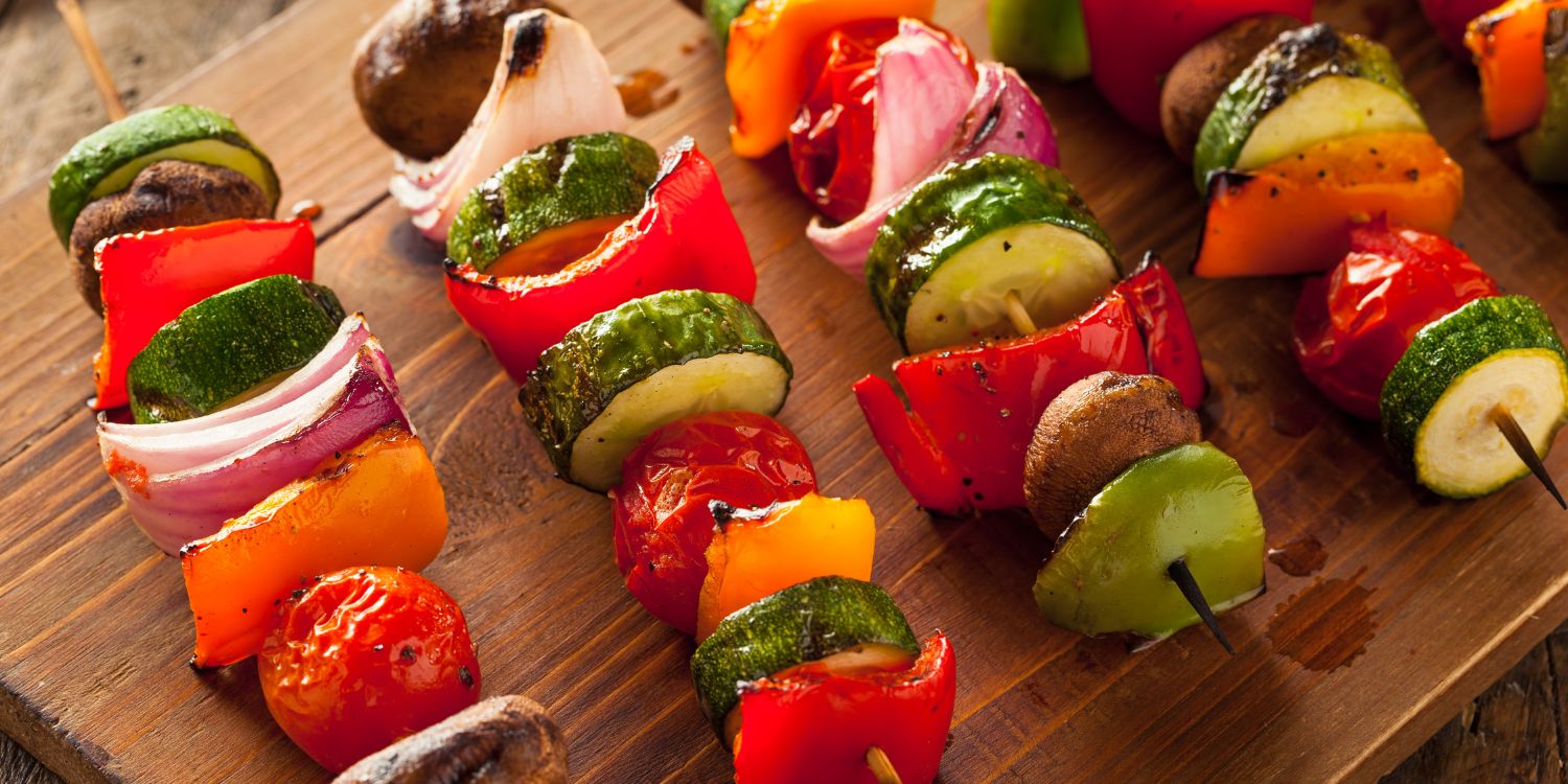 Auf einem Holzbrett liegen Spieße mit verschiedenen Gemüsestücken, wie Paprika, Zucchini und Zwiebeln.. Artikel "Clever grillen mit Jodsalz" öffnen.