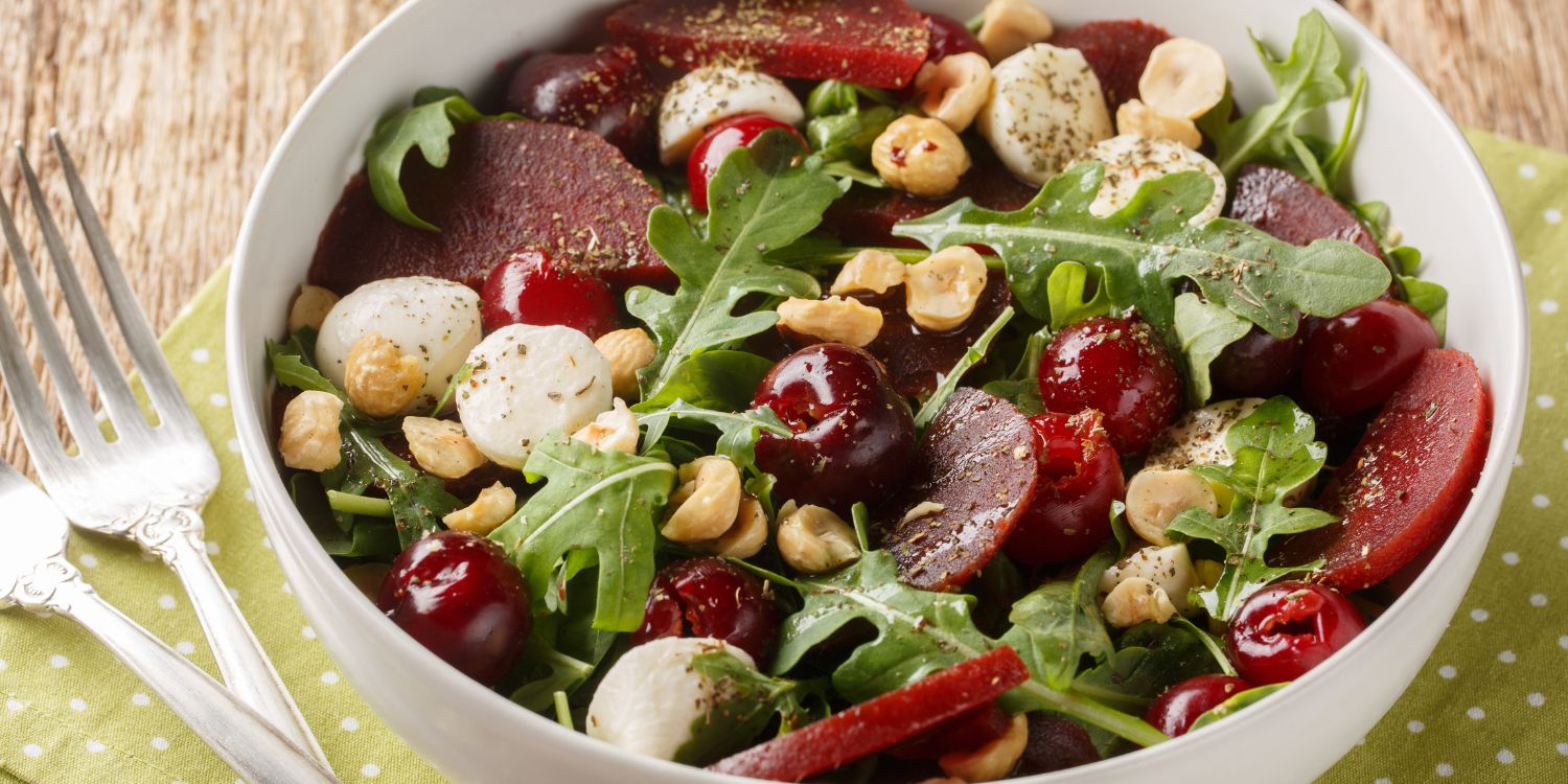 Auf einem Tisch steht eine weiße Schüssel mit Rucola, Roter Bete, Mozzarella und Haselnüssen.. Artikel "Haselnüsse: Herbstgenuss mit Biss" öffnen.