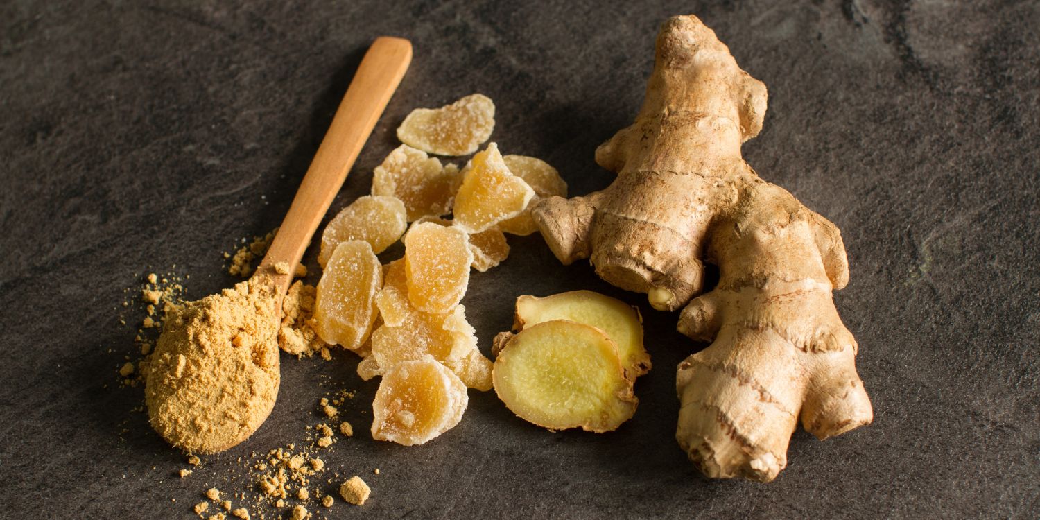 Eine Ingwerwurzel, kandierter Ingwer und Ingwerpulver in einem Holzlöffel liegen auf grauem Betonhintergrund.. Artikel "Ingwer – die scharfe Knolle" öffnen.