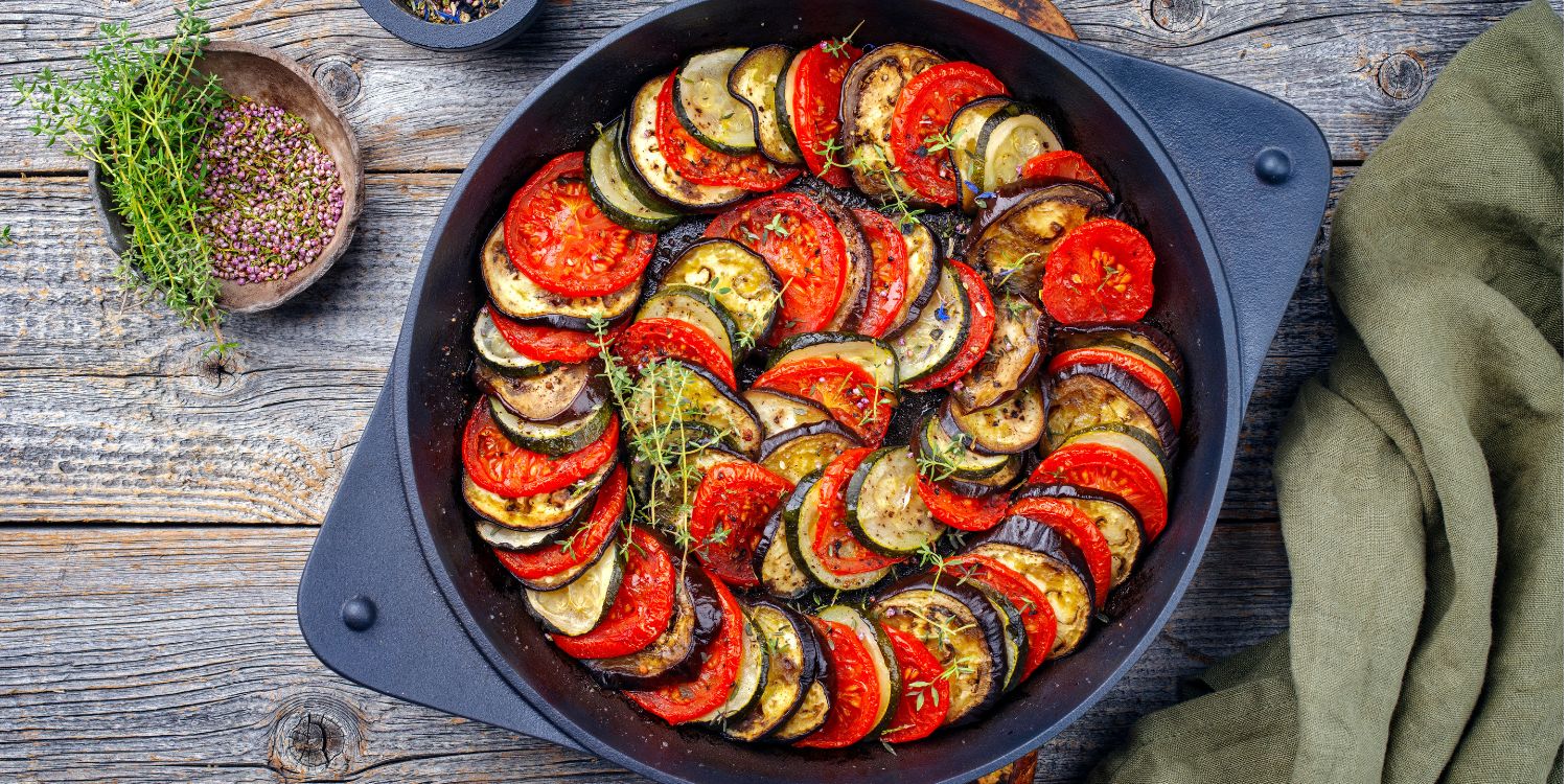 Traditionelle französische Ratatouille im modernen Stil mit Tomaten, Auberginen, Zucchini und  Kräuter der Provence, serviert in einer rustikalen gusseisernen Pfanne.. Artikel "Kräuter der Provence" öffnen.