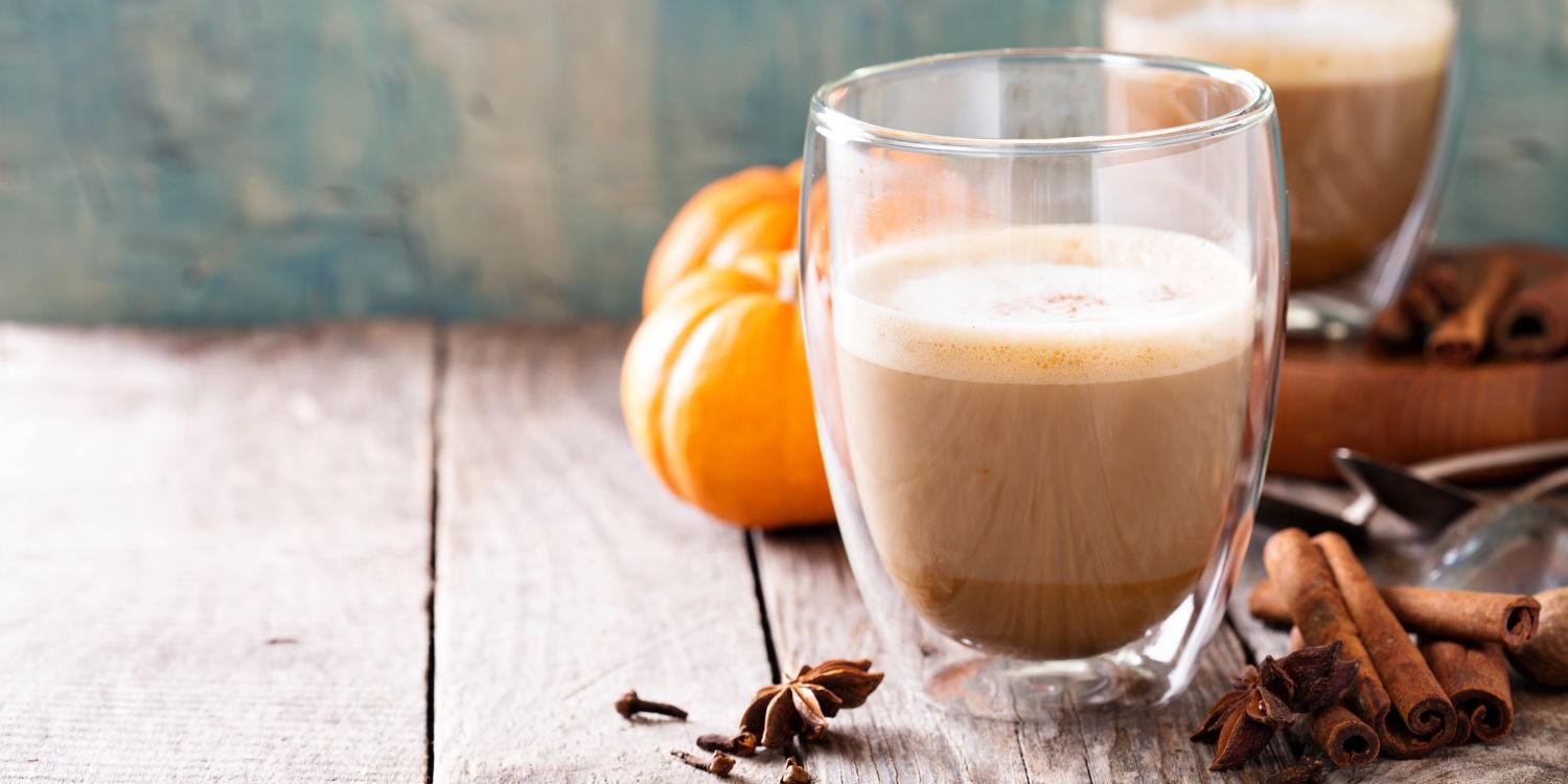  Ein Glas Pumpkin Spice Latte mit etwas Milchschaum steht vor kleinen Kürbissen auf einem Holztisch. Neben dem Glas liegen Zimtstangen und Sternanis. . Artikel "Kürbisgetränke – einfach selbstgemacht" öffnen.