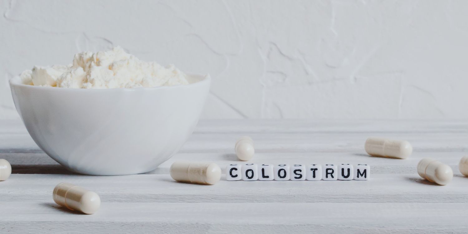 Auf einem weißen Tisch steht eine weiße Schüssel mit Pulver, daneben liegen weiße Kapseln und Buchstabenwürfel die das Wort Colostrum bilden.. Artikel "Lactoferrin – Hoffnung oder Hype?" öffnen.