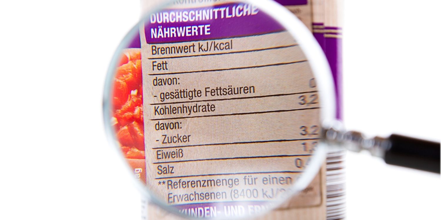 Durch eine Lupe wird die Kennzeichnung einer Konservendose vergrößert, sodass man die durchschnittlichen Nährwerte erkennen kann.. Artikel "Zutatenliste, Werbung und Co. richtig verstehen" öffnen.