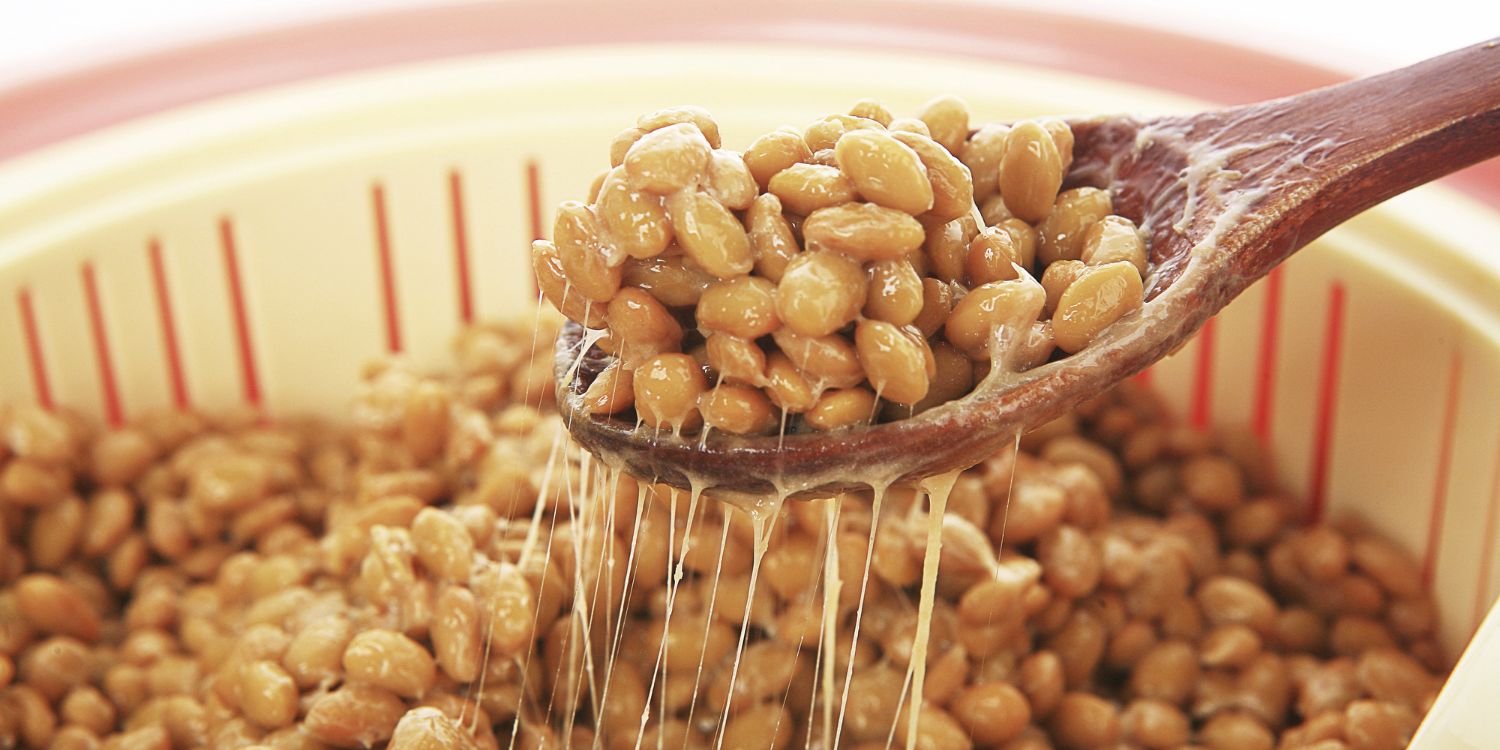 Mit einem Löffel werden fermentierte Sojabohnen aus einer Schüssel gehoben und ziehen Fäden.. Artikel "Natto – klebrig und gesund" öffnen.