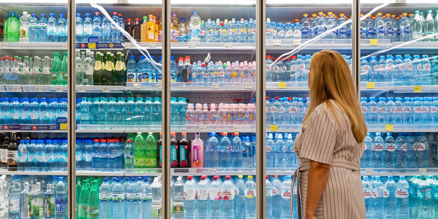 Eine Frau steht vor der großen Auswahl an Getränken im Kühlregal eines Supermarkts. . Artikel "Trend: Near-Water-Getränke" öffnen.