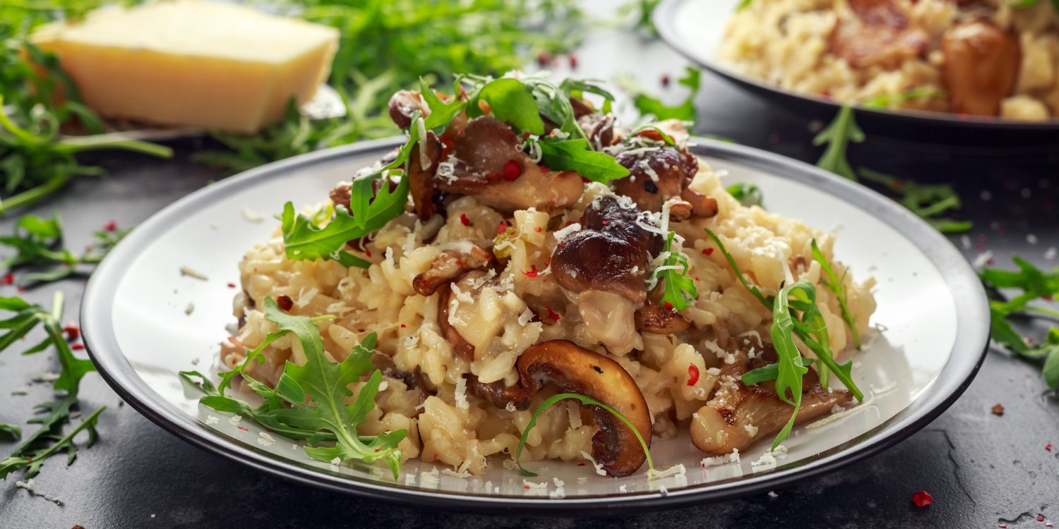 Auf einem Teller ist ein Pilzrisotto mit Parmesan und Rucola als Topping angerichtet.. Artikel "Schnelle Küche mit Pilzen" öffnen.
