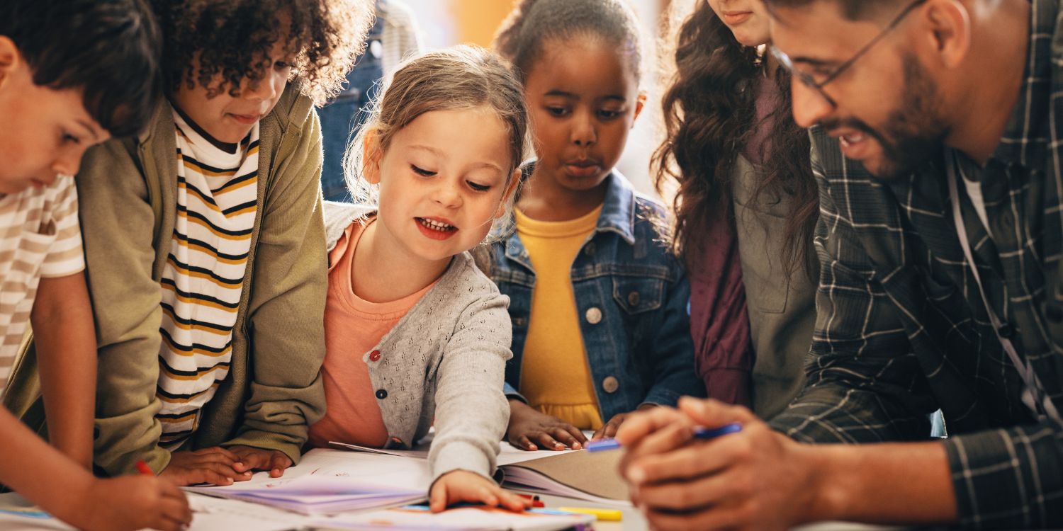 Ein Lehrer und mehrere Grundschulkinder stehen um einen Tisch und beugen sich über verschiedene Materialien.. Artikel "Spannende Missionen für Schulkinder" öffnen.