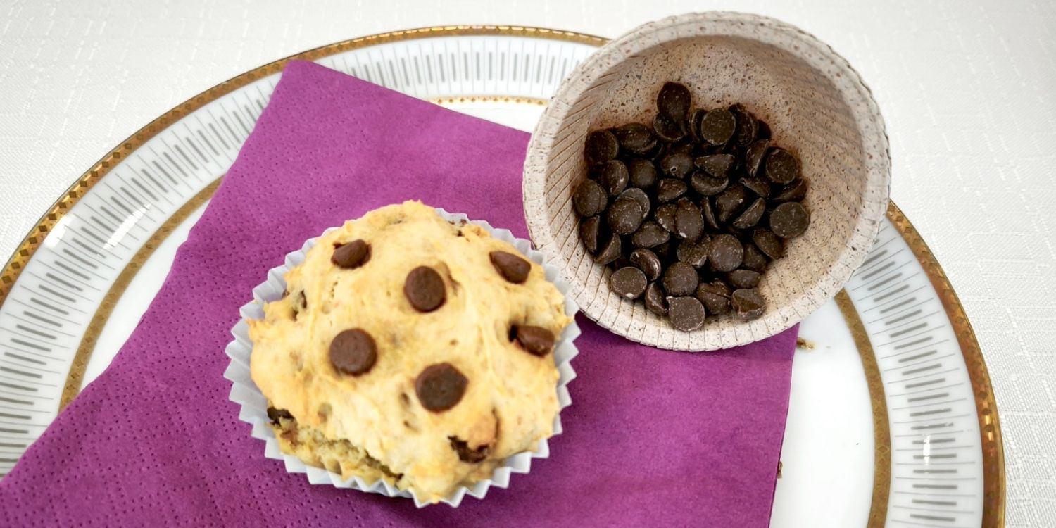 Auf einem Teller liegt ein Muffin mit Stückchen einer Schokoladenalternative ohne Kakao. . Artikel "„Schokolade“ ohne Kakao" öffnen.