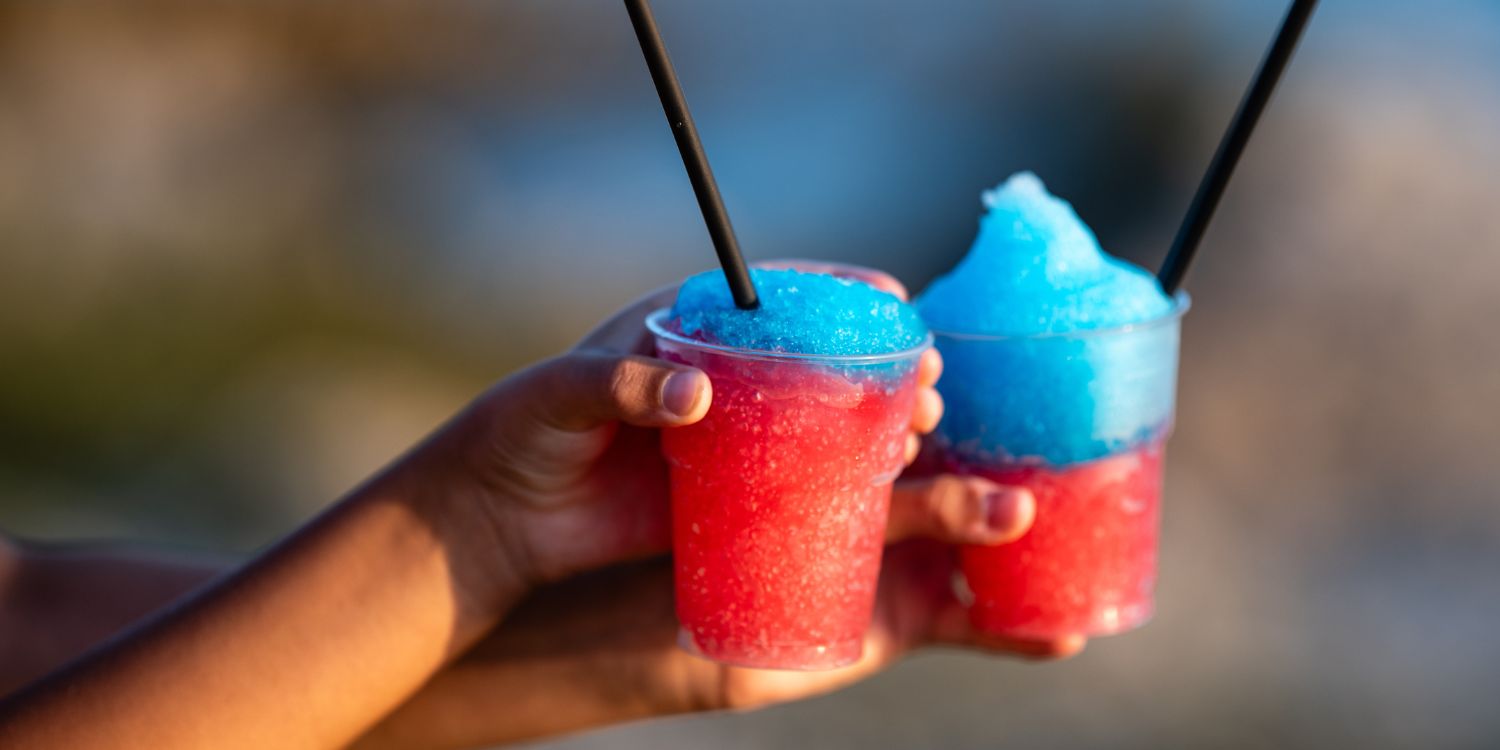 Zwei Hände halten zwei rot-blaue Slush-Eis-Getränke.. Artikel "Wie sicher sind Slush-Ice-Getränke?" öffnen.