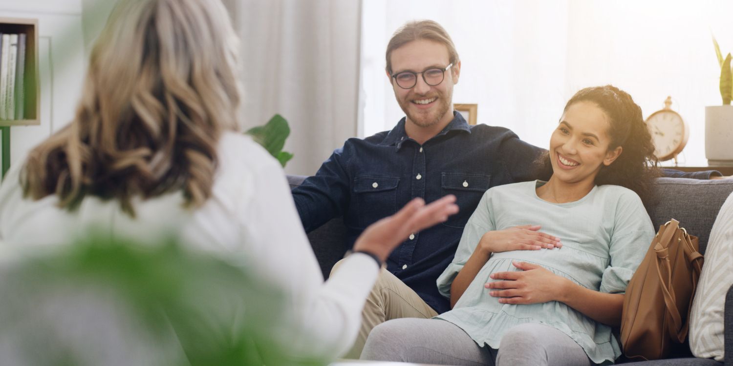 Ein werdendes Elternpaar wird von einer Hebamme in einer Praxis beraten.. Artikel "Besser in die Stillzeit starten" öffnen.