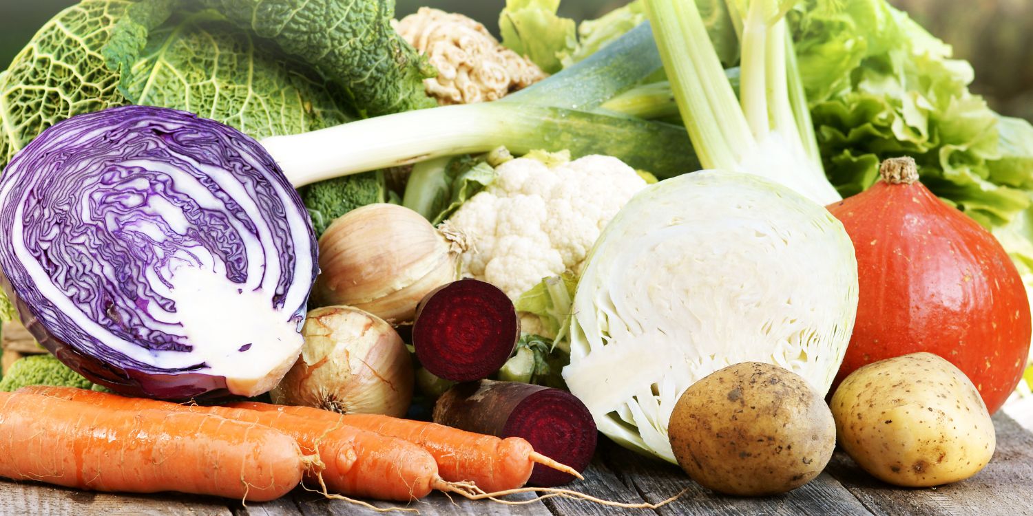 Auf einem Tisch liegen halbierter Rot- und Weißkohl, Hokkaido, Möhren, rote Bete, Blumenkohl, Kartoffeln, Lauch, Wirsing, Salat und Zwiebeln.. Artikel "„Regionale Vielfalt – Saisonal genießen“" öffnen.